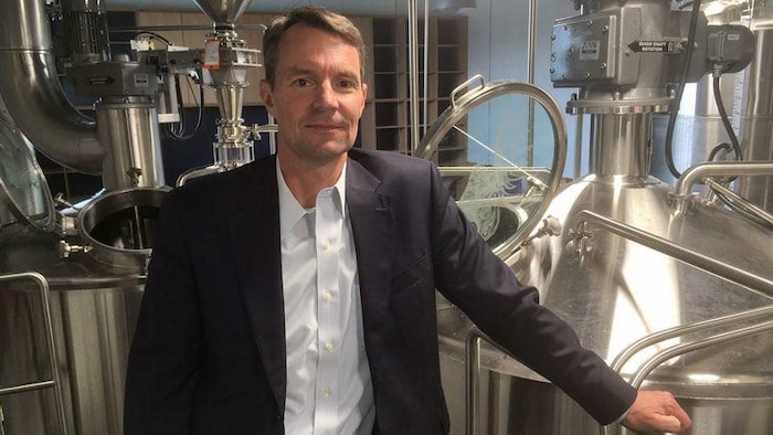 Andrew Oland devant des cuves dans une brasserie.