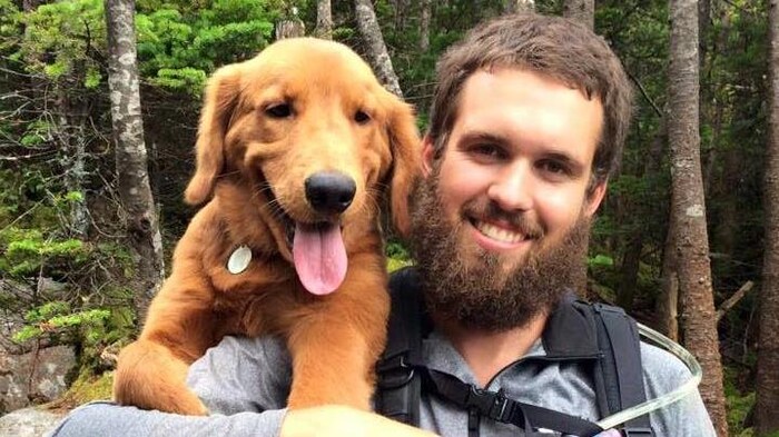 Olivier Bruneau tient son chien sur son épaule.