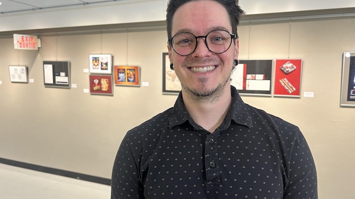 Un homme devant des tableaux accrochés au mur.