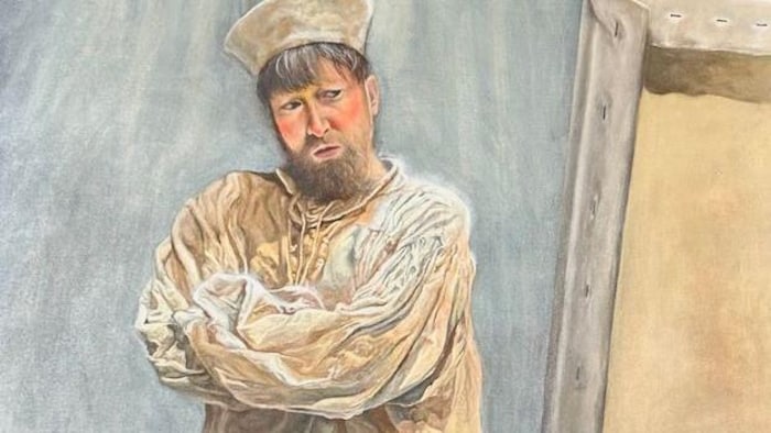 Un homme fixe une peinture.
