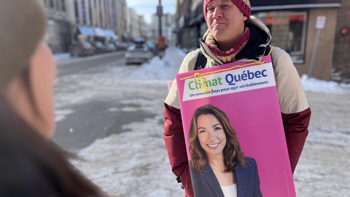 Un homme tient une pancarte électorale.
