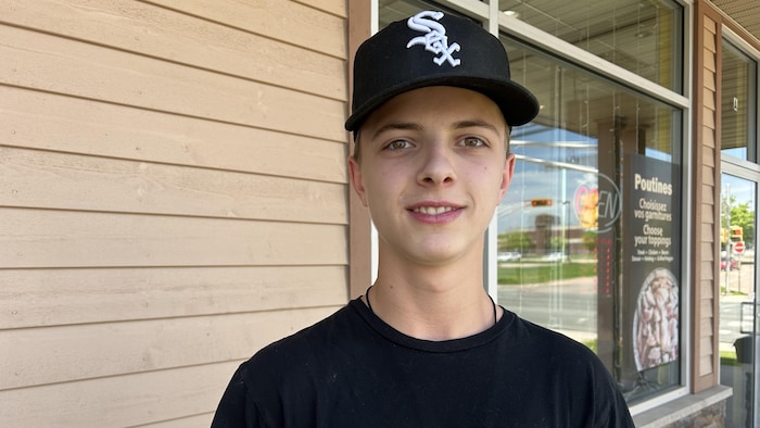 Un adolescent devant un mur extérieur de restauration rapide.