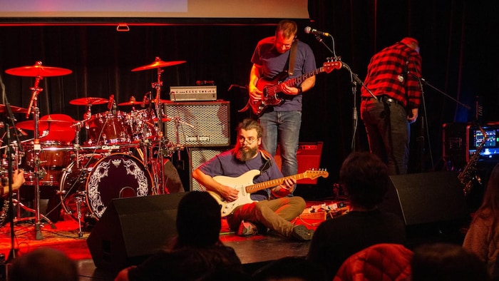 Olivier Provencher St-Pierre assis sur scène avec sa guitare. 