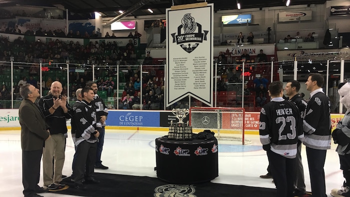 Des anciens joueurs regardent la bannière pour les 20 ans de la conquête de la Coupe Memorial par les Olympiques de Gatineau