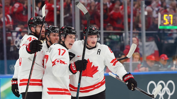Quatre joueurs du Canada se font l'accolade sur la glace.