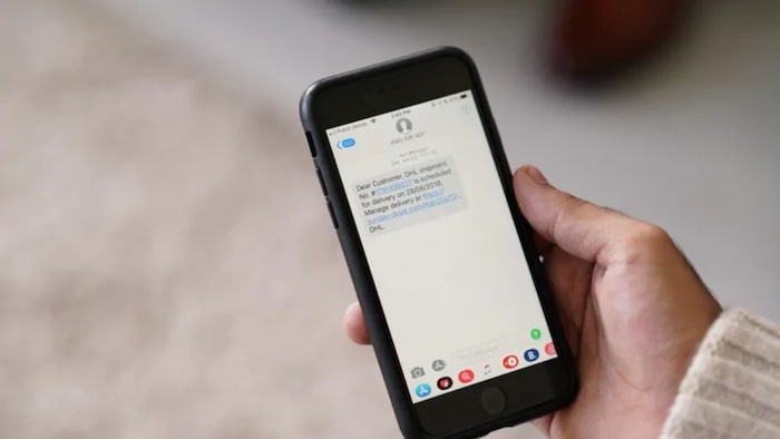 Une main tient un cellulaire, en gros plan. 