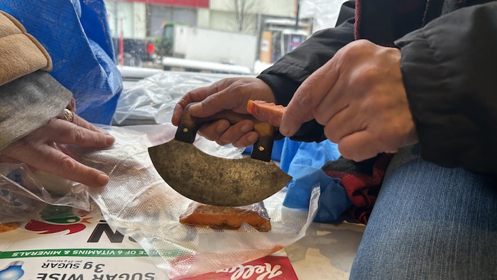 Une femme coupe un morceau de poisson.