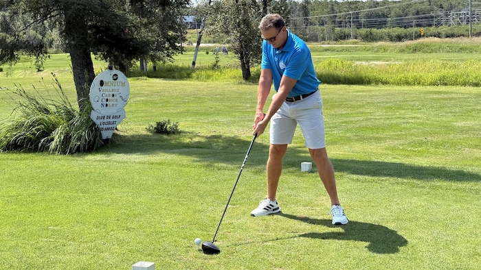 Jacques Larrivée adresse sa balle avec son driver sur le tertre de départ d'un terrain de golf.