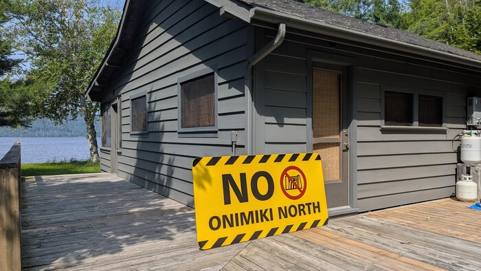 Un panneau jaune et noir inscrit « No Onimiki North » est accotée sur un chalet.