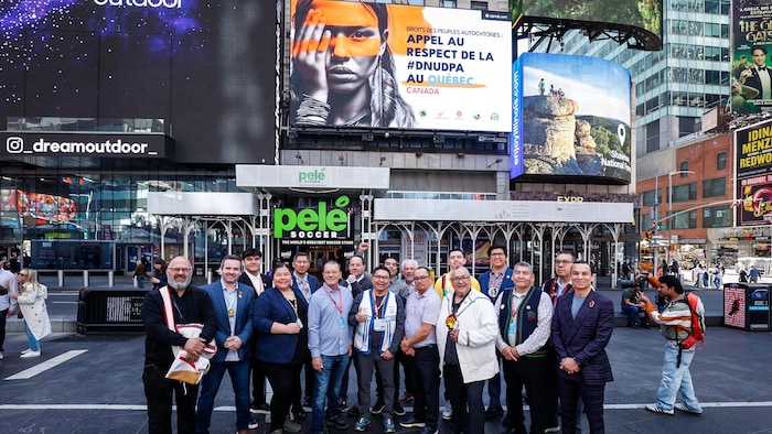 De gens posent devant un écran.