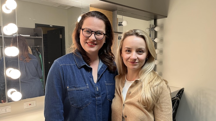 Deux femmes sourient à la caméra dans une loge.
