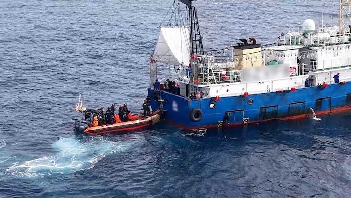 Un petit bateau approche un gros bateau de pêche.