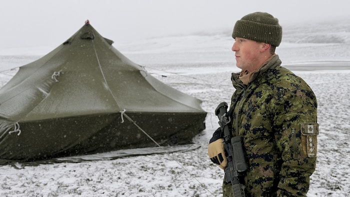Le capitaine Miguel Fournier portant une arme, devant une tente dans l'Arctique.