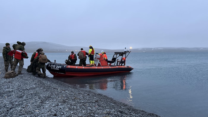 Des membres de la Garde côtière canadienne et des militaires en train de monter à bord d'un bateau pneumatique, sur la rive de Resolute Bay, en septembre .