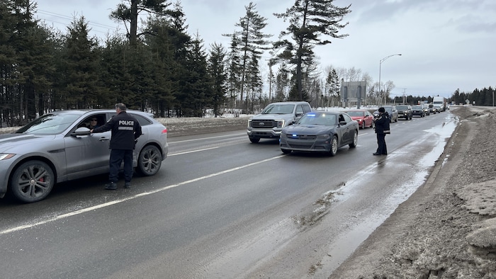 Des policiers interceptent des véhicules en file à l'entrée de la réserve faunique des Laurentides.