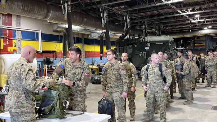 Des militaires en file avec leurs sacs à dos.