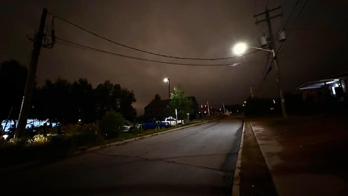 Lampadaires allumés au-dessus d'une route et d'un stationnement. 