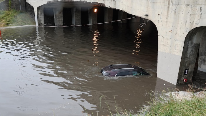 En raison des fortes pluies, une voiture s'est retrouvée coincée sous le viaduc Salaberry dans l'arrondissement Ahuntsic-Cartierville, à Montréal, le 13 juillet 2025.