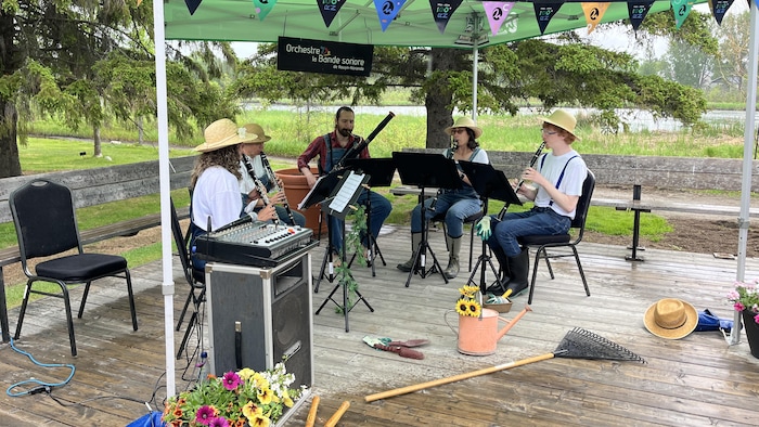 Cinq musiciens portant des costumes d'horticulteurs jouent de la musique au parc botanique.