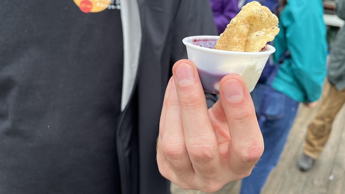 Une main tient une bouchée présentée dans un petit contenant de plastique.