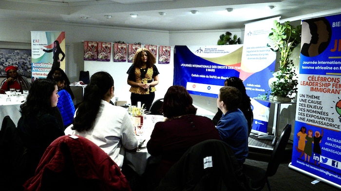 Des personnes sont assises à des tables devant des affiches d'organismes. 
