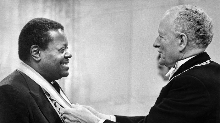 Un homme met une médaille d'honneur autour du cou du pianiste.