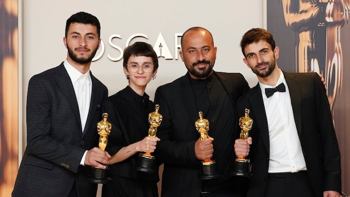 Trois hommes et une femme posent tenant chacun un Oscar.