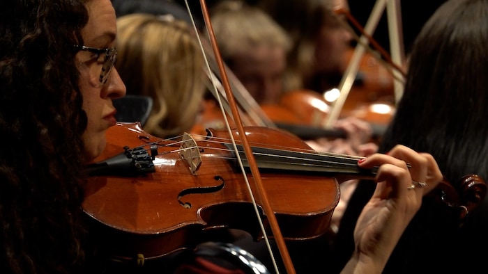 Noémie Charbonneau joue du violon lors d'un spectacle avec d'autres musiciens.