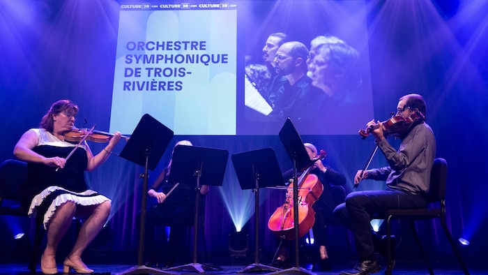 Des violonistes jouent sur une scène. 