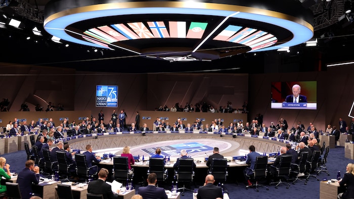 Les locaux du sommet de l'OTAN sont occupés par les dirigeants des pays membres, assemblés autour d'une grande table ronde.