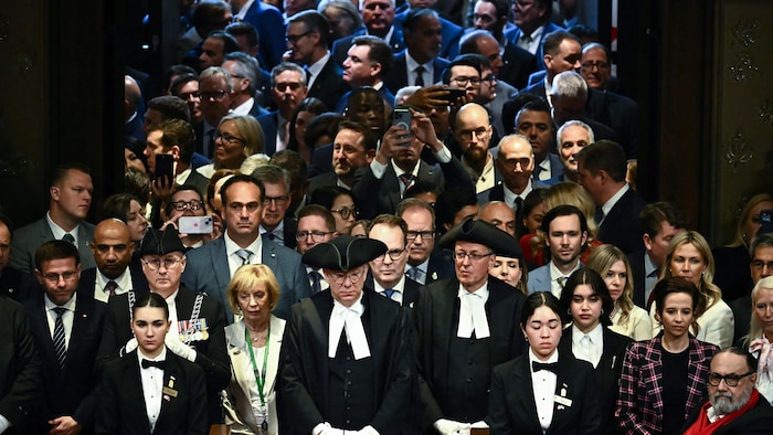 Les députés sont à l'entrée du Sénat pour écouter la lecture du discours du Trône par le roi Charles III.