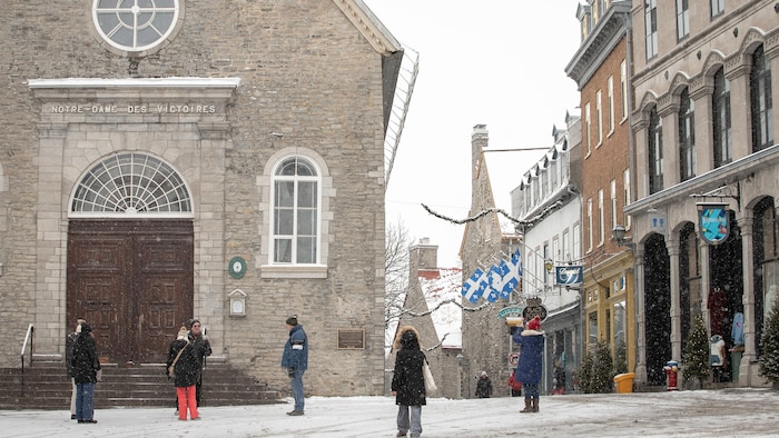 Des touristes regardent et photographies l'église Notre-Dame-des-Victoires dans le Petit-Champlain.