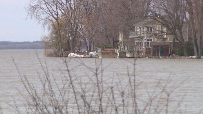 De l'eau se rapproche d'une maison située aux abords de la rivière des Outaouais.