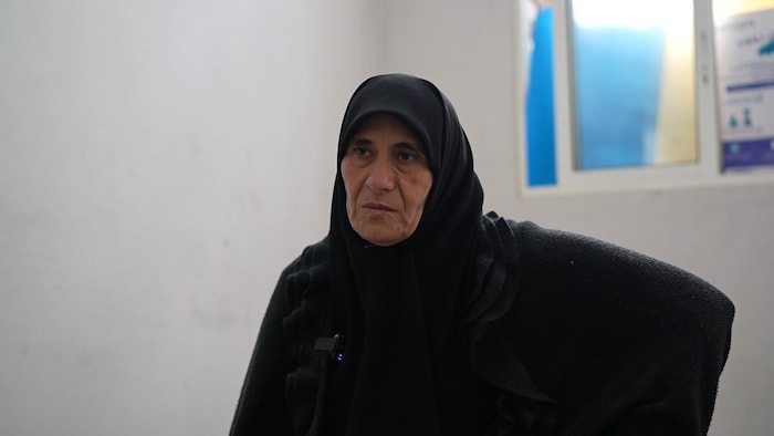 Une femme drapée de noir est assise.