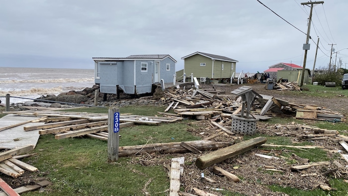 Des maisons sur le bord de l'eau. Tout le secteur est jonché de bois et de débris amenés par l'ouragan. Un trottoir de bois est à moitié détruit.