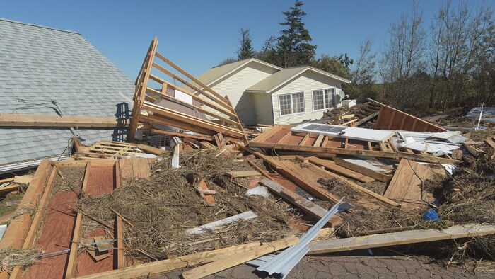 De gros morceaux de bois provenant de deux habitations endommagées par l'ouragan jonchent le sol.