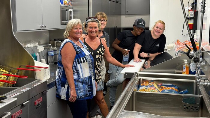 Cinq femmes sont debout dans la cuisine.