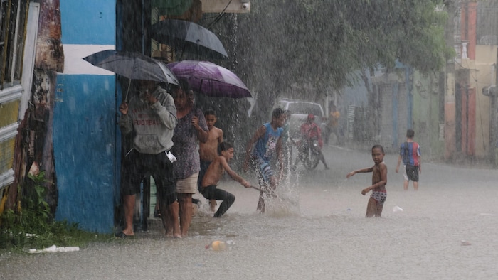 Des enfants jouent dans une rue inondée par les pluies.