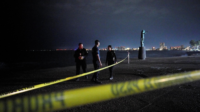 Des agents de la police municipale se tiennent derrière une zone bouclée le long du front de mer alors que l'ouragan Simon s'approche de la côte pacifique du Mexique, à Puerto Vallarta, le 11 octobre 2026.