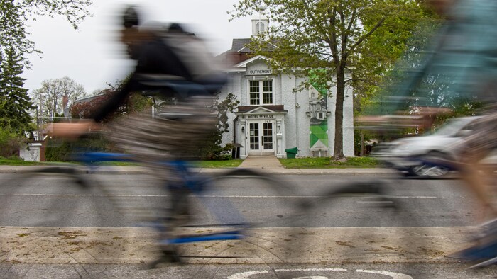 Des cyclistes passent devant la mairie d'Outremont.