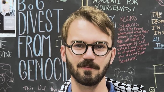 Le trésorier devant un tableau rempli de messages de soutien à la cause palestinienne