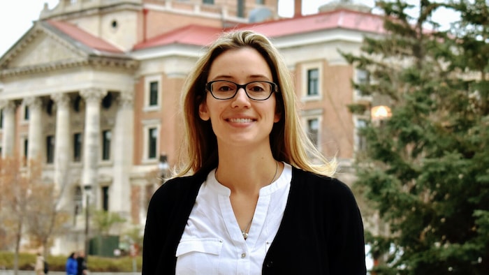 Natalie Riediger à l'extérieur devant un bâtiment et à côté d'un arbre.