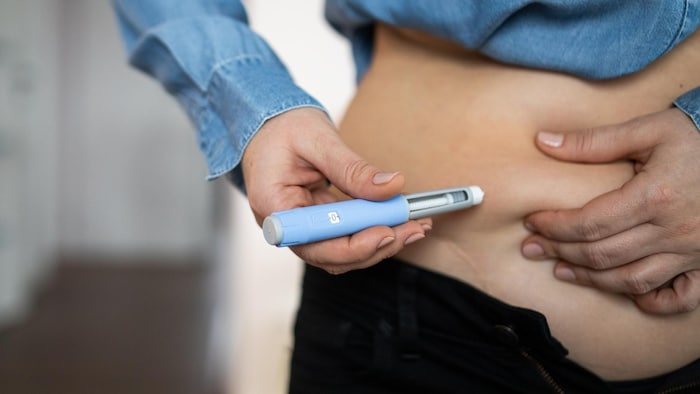 Une personne se fait une injection dans le ventre. 