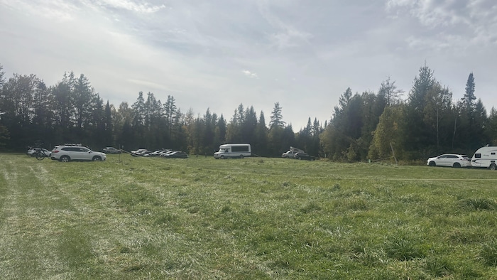 Quelques voitures et campeurs sont stationnés dans cet espace gazonné.