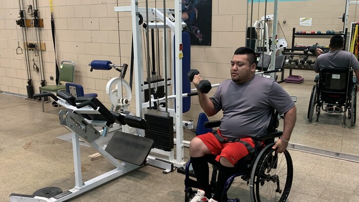 Un homme en fauteuil roulant soulève des poids.
