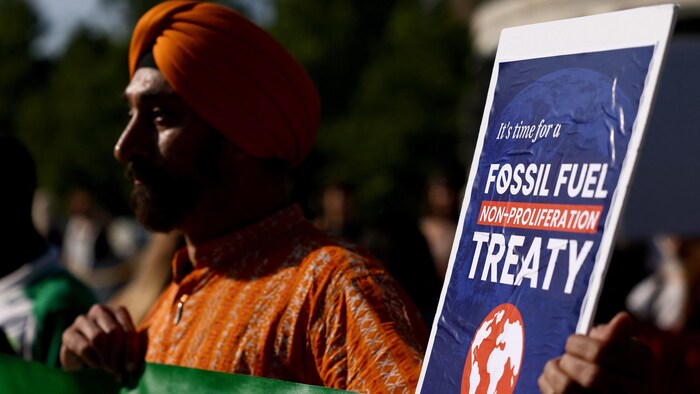 Un manifestant tient une pancarte sur laquelle on peut lire: «Il est temps d'avoir un traité de non-prolifération des énergies fossiles».