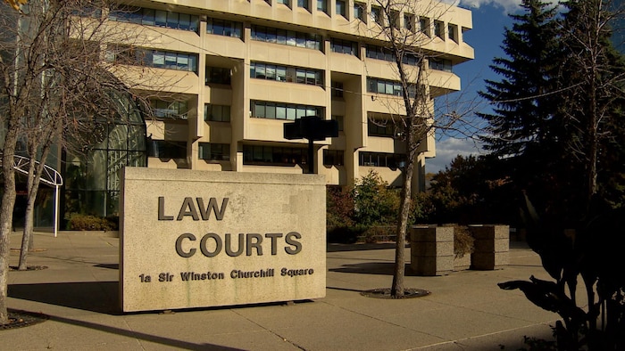 L'enseigne devant le palais de justice d'Edmonton avec le bâtiment en arrière-plan.