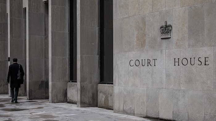 Un homme marche devant le palais de justice de l’avenue University à Toronto.