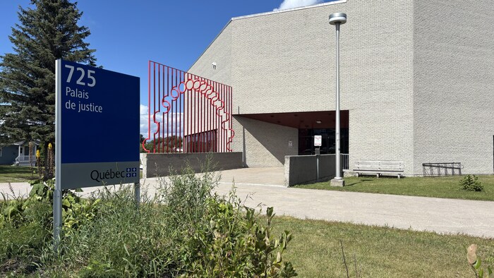 Un panneau devant un grand bâtiment en briques annonce un palais de justice.
