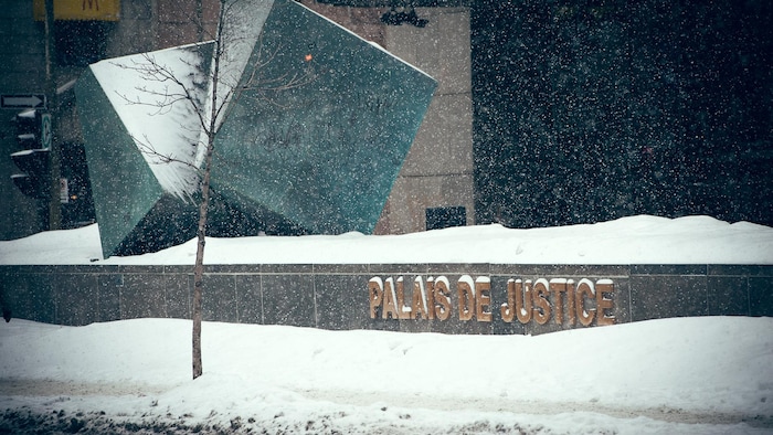 La neige tombe sur l'enseigne du Palais de justice de Montréal, sur la rue Notre-Dame, dans le Vieux-Montréal.